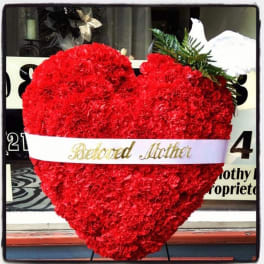 Heart-shaped red carnation arrangement with a white ribbon