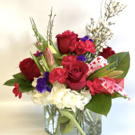 Red roses and mixed flowers in a square glass vase with heart ribbon