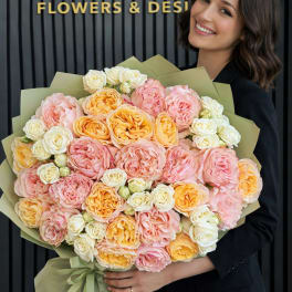 Woman holding a large bouquet of pink, peach, and white roses