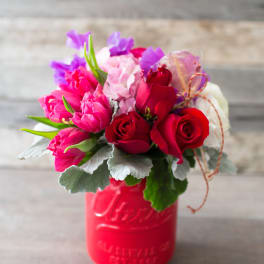 Bouquet of red and pink roses in a red mason jar