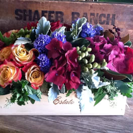 Mixed floral arrangement in a wooden box with roses and hydrangeas