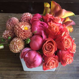 Pink and coral flowers arranged in a white vase
