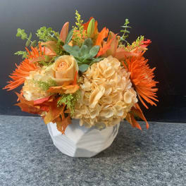 Orange and cream floral arrangement in a white vase