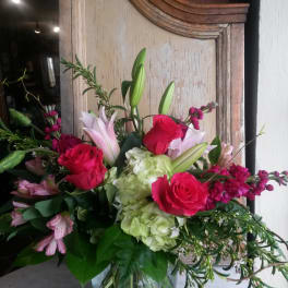 Bouquet of pink roses, lilies, and hydrangeas in a glass vase