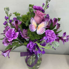 Purple bouquet in a glass vase with a butterfly decoration
