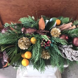 Holiday centerpiece with evergreen branches, pinecones, oranges, and cinnamon sticks