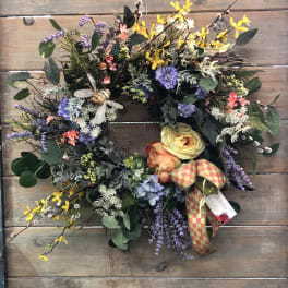 Colorful floral wreath with yellow, purple, and peach blooms on a wood background