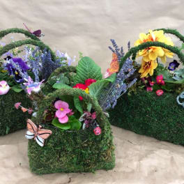 Three moss-covered baskets with colorful flowers and butterfly decorations