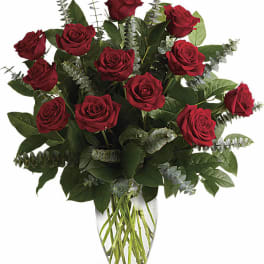 Red roses arranged in a clear glass vase with eucalyptus accents