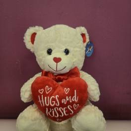 White teddy bear holding a red heart pillow