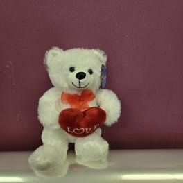 White teddy bear holding a red heart with a ribbon