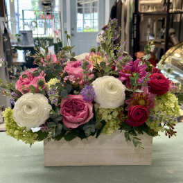 Mixed pink and white flowers arranged in a wooden box