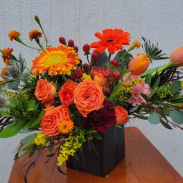 Orange and yellow floral arrangement in a black vase