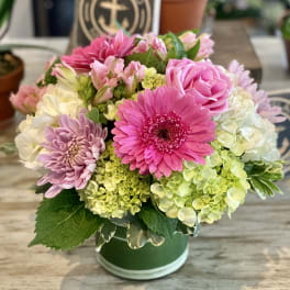 Pink and lavender flowers arranged in a green hatbox