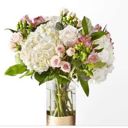 White hydrangeas and pale pink roses in a clear glass vase