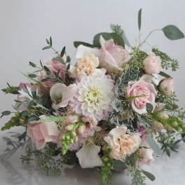 Soft pink and white bouquet with roses, calla lilies, and a central dahlia