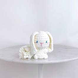 White plush bunny figurine beside a white carnation on a round table