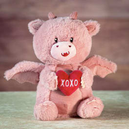 Pink plush teddy bear holding a red heart that says XOXO