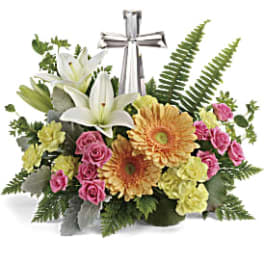 Floral arrangement with white lilies, pink roses, and a silver cross