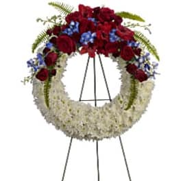 Standing floral wreath with red and white flowers on an easel