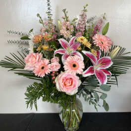 Pink lilies, roses, and gerbera daisies in a glass vase