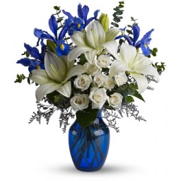 White lilies and roses with blue irises in a blue vase