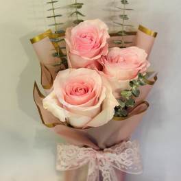 Bouquet of pink roses wrapped in blush paper with a lace ribbon