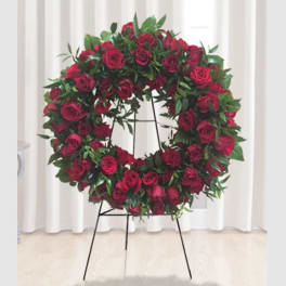 Circular wreath of red roses on a black stand