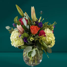 Mixed bouquet with roses, lilies, and hydrangeas in a glass vase