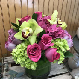 Pink roses and green hydrangeas in a glass vase with pale green orchids