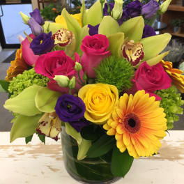 Colorful bouquet of roses, lilies, and gerbera daisies in a glass vase