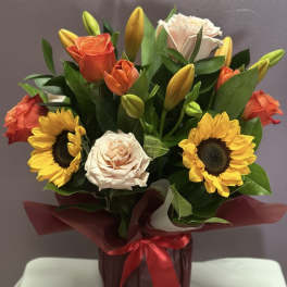 Bouquet of roses, sunflowers, and lilies in a wrapped container