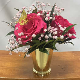 Pink roses in a gold vase with baby's breath and a butterfly pick