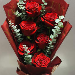 Bouquet of red roses wrapped in burgundy paper with eucalyptus accents