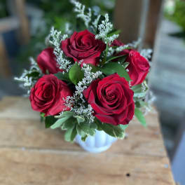 Bouquet of red roses with white filler in a small vase