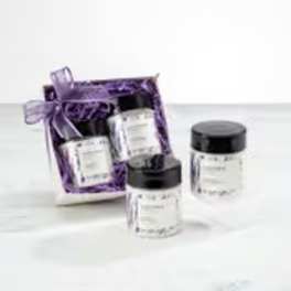 Gift set of small white jars with black lids in a purple ribboned box