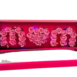 Pink box of roses spelling MOM with a heart shape in the center and small colored lights inside