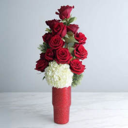 Tall red vase with a column of red roses above a white hydrangea cluster