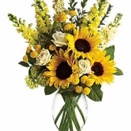 Tall bouquet of yellow sunflowers and white roses in a clear glass vase