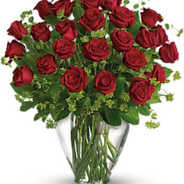 Large bouquet of long-stemmed red roses with green filler in a clear glass vase