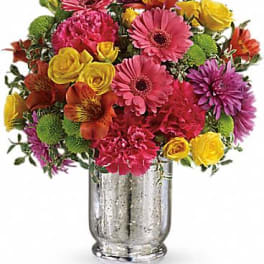 Bright mixed bouquet with pink gerbera daisies and yellow roses in a silver vase