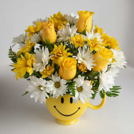 Yellow roses and white daisies in a smiley-face mug