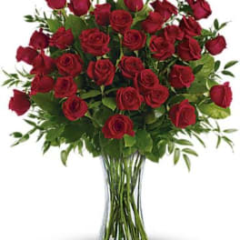Tall bouquet of long-stemmed red roses in a clear glass vase