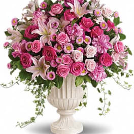 Large pink and white rose and lily arrangement in a white pedestal urn