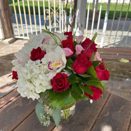 Bouquet of red roses, white hydrangea, and white orchids in a glass vase