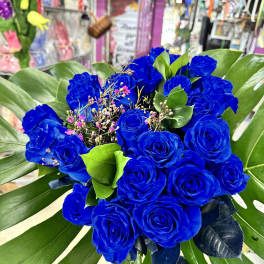 Bouquet of vivid blue roses with large tropical leaves