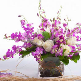 Purple orchid bouquet with white roses in a glass vase