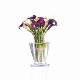 Bouquet of purple and white calla lilies in a clear glass vase