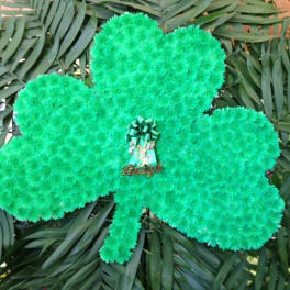 Green shamrock-shaped floral display with a ribbon centerpiece
