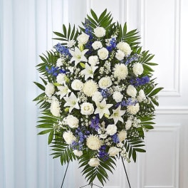 Standing funeral spray of white and blue flowers on an easel